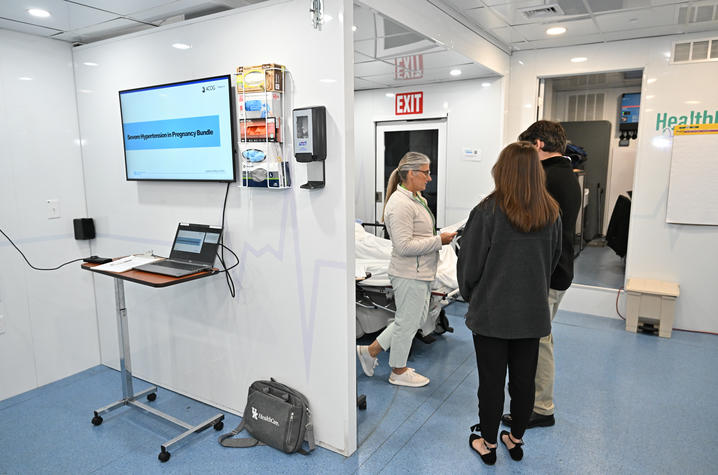 Three people in a hospital room looking at a chart. 