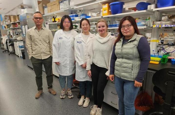 Five people standing in a lab facing the camera.