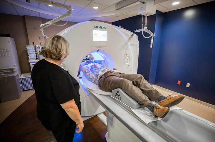 Man going through a circular medical device; woman standing next to the man. 