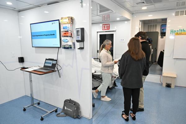 Three people in a hospital room looking at a chart. 