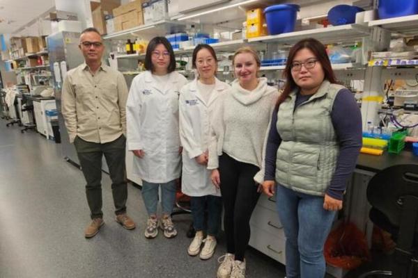 Five people standing in a lab facing the camera.