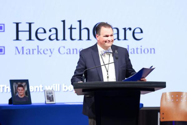 Man standing behind a podium holding a folder. 