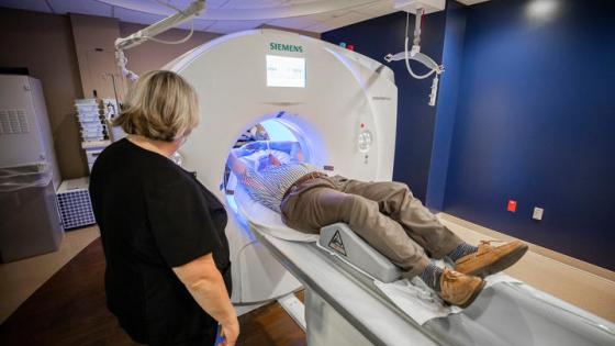 Man going through a circular medical device; woman standing next to the man. 