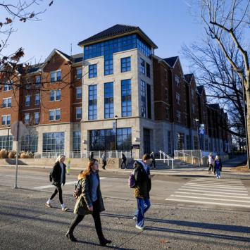 Students pass along the sidewalk in front of the Lewis Honors College.